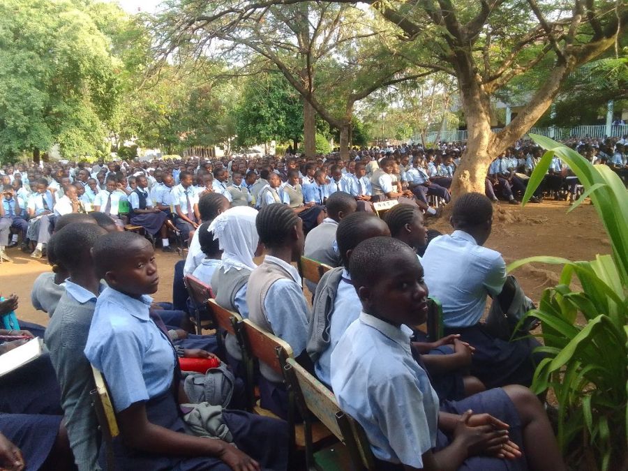 Hundreds of school students seated outdoors under trees during an MBB mentorship session in Kenya